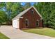Detached brick garage with a white door and adjacent outdoor fireplace; paved driveway and lush lawn at 121 Westchase Run, Sanford, NC 27330