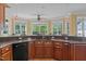 Modern kitchen with granite countertops, wooden cabinets, a black dishwasher, and a sink with a view at 121 Westchase Run, Sanford, NC 27330