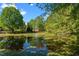 Picturesque view of a serene pond with reflections of lush trees and a clear blue sky, creating a peaceful ambiance at 121 Westchase Run, Sanford, NC 27330