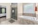 Well-lit bathroom with glass-enclosed shower and soaking tub under window at 12308 Bunchgrass Ln, Raleigh, NC 27614