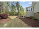 Backyard view of landscaped flowerbeds, stone patio, and wooded play area at 1305 Reservoir View Ln, Wake Forest, NC 27587
