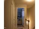 Hallway view showing doorway, neutral colors and a peek at the living room with comfortable chair and shelving at 1505 Kendall Dr, Durham, NC 27703
