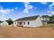 The backyard of a modern home features a wooden deck, white siding, and a spacious, freshly seeded yard at 203 Sourgum Ct, Zebulon, NC 27597
