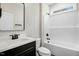 Bathroom with modern vanity, mirror, toilet, and tub with tiled walls and a small window at 203 Sourgum Ct, Zebulon, NC 27597