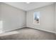 Neutral bedroom with gray carpet, white trim, window view of house under construction, and electrical outlets at 203 Sourgum Ct, Zebulon, NC 27597