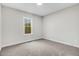 Neutral bedroom with gray carpet, white trim, window with leafy tree view, and electrical outlets at 203 Sourgum Ct, Zebulon, NC 27597