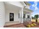 Inviting front porch featuring brick steps, black railing, black front door, and stylish architectural details at 203 Sourgum Ct, Zebulon, NC 27597