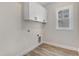 Bright laundry room features white cabinets, a window, and wood-look flooring at 203 Sourgum Ct, Zebulon, NC 27597