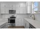 A modern kitchen boasts white cabinets, stainless appliances, and a tiled backsplash at 241 Connelly Way, Zebulon, NC 27597