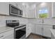 A modern kitchen boasts white cabinets, stainless appliances, and a tiled backsplash at 241 Connelly Way, Zebulon, NC 27597