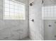 A gorgeous marble-tiled shower featuring a window and bronze shower head at 241 Connelly Way, Zebulon, NC 27597