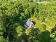 Aerial view of a well-maintained property with a house, lush trees, manicured lawn, and gravel drive in a serene setting at 2509 Nc 57, Hillsborough, NC 27278