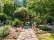 Stone pathway leads through landscaped greenery and a charming wooden gate and fence at 2509 Nc 57, Hillsborough, NC 27278