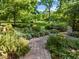 Beautifully landscaped backyard featuring brick pathways, lush greenery, and mature trees at 2509 Nc 57, Hillsborough, NC 27278
