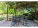 Relaxing outdoor stone patio features a metal table, chairs, and lush greenery overhead at 2509 Nc 57, Hillsborough, NC 27278