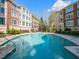 Resort-style swimming pool surrounded by lush landscaping and multi-story brick buildings on a sunny day at 2813 Market Bridge Ln # 204, Raleigh, NC 27608