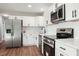 Updated kitchen featuring stainless steel appliances, white cabinets, modern fixtures, and laminate flooring at 305 Gillis Rd, Roxboro, NC 27574