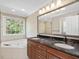 Bathroom featuring dual sinks, granite counters, tub, and natural light at 308 Sunset Creek Cir, Chapel Hill, NC 27516