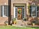 Close-up of front entry door with wreath, sidelights, planters, and brick facade at 308 Sunset Creek Cir, Chapel Hill, NC 27516