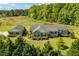 Aerial view shows the house with an attached garage, surrounded by large grass and mature trees at 3604 Stagecoach Rd, Durham, NC 27713
