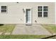 Home's back door leads to a concrete patio and grassy lawn, framed by two windows on a tan-colored exterior at 3819 Valleydale Dr, Durham, NC 27703