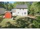 Spacious backyard with green lawn, a charming red shed, and the home's exterior surrounded by mature trees at 3819 Valleydale Dr, Durham, NC 27703
