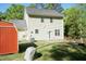 Sunlit backyard with a well-maintained lawn, a red shed, and the home's tan siding under a clear sky at 3819 Valleydale Dr, Durham, NC 27703