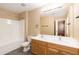 Bathroom with double sink vanity, toilet, shower-tub combo, and an open doorway leading into the bedroom at 3819 Valleydale Dr, Durham, NC 27703