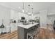 Modern white kitchen with island, seating, pendant lights, and stainless steel appliances at 3908 Booker Ave, Durham, NC 27713