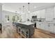 Bright kitchen featuring a large island with seating, white cabinets, stainless steel appliances, and hardwood floors at 3908 Booker Ave, Durham, NC 27713