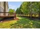 A spacious backyard with a wooden deck, manicured lawn, and a line of evergreen trees along the fence line at 4112 Riverport Rd, Raleigh, NC 27616