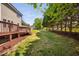 The backyard features a spacious lawn, bordered by a wooden fence and lush trees, accessible from a raised wooden deck at 4112 Riverport Rd, Raleigh, NC 27616