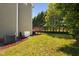 A view of the backyard from the side of the house showcases a wooden deck, grass, and privacy trees at 4112 Riverport Rd, Raleigh, NC 27616