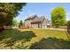 Beautiful backyard with a well-maintained lawn, mature trees, black fence, and a view of the home's exterior and deck at 4112 Riverport Rd, Raleigh, NC 27616