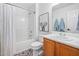 Bright bathroom with geometric tiled floor, white shower with curtain, white toilet, and brown vanity at 4112 Riverport Rd, Raleigh, NC 27616