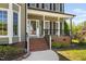 Inviting front porch with brick steps, white columns and black metal railing at 4112 Riverport Rd, Raleigh, NC 27616