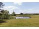 Scenic view of a pond with a dock surrounded by a large grassy field and lush trees at 481 Firetower Rd, Louisburg, NC 27549