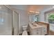 Bathroom with double sink vanity and tub with shower behind a glass door at 4828 Forest Highland Dr, Raleigh, NC 27604