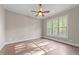 Sunlit bedroom with hardwood floors, ceiling fan, and large windows at 4924 Theys Rd, Raleigh, NC 27606