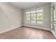 Bright, empty room with hardwood floors, neutral paint, large window, and outdoor access at 4924 Theys Rd, Raleigh, NC 27606