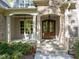 Close-up of a home's front porch with stone archway, double wood doors, and lush landscaping at 4924 Theys Rd, Raleigh, NC 27606