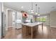 Open-concept kitchen with large island, wooden floors, stainless steel appliances, and custom hood vent at 4924 Theys Rd, Raleigh, NC 27606