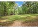 Spacious backyard showing the house and a storage building, nestled amongst mature trees at 6121 Kelvin Dr, Durham, NC 27712