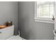 Small bathroom area with toilet, small window, and a shelf for storage at 6907 Field Hill Rd, Raleigh, NC 27603