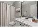Bathroom with a white vanity, black fixtures, a decorative mirror, and a neutral-toned shower curtain at 72 Cokesbury Park Ln, Fuquay Varina, NC 27526
