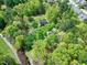 Aerial view of a brick home nestled in lush greenery with a winding driveway at 8120 Stillbreeze Dr, Fuquay Varina, NC 27526