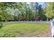 Private backyard featuring a white picket fence, manicured lawn, and vibrant flowering bushes at 8120 Stillbreeze Dr, Fuquay Varina, NC 27526