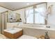 Large bathtub beneath a bright window with decorative curtains, as well as a glass shower with an open door at 8120 Stillbreeze Dr, Fuquay Varina, NC 27526