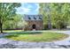 Traditional brick home with dormer windows surrounded by lush green trees and mature landscaping at 8120 Stillbreeze Dr, Fuquay Varina, NC 27526