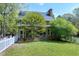 Charming home exterior with a screened porch, brick facade, white picket fence, and lush green lawn at 8120 Stillbreeze Dr, Fuquay Varina, NC 27526